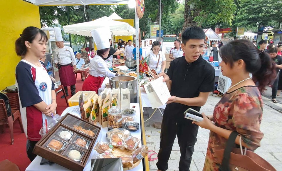 ភ្ញៀវទេសចរណ៍រីករាយនឹងនំព្រះខែហាណូយក្នុងពិធីបុណ្យ។ រូបថត៖ Hoai Nam