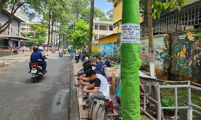 Mẫu giấy rao vặt dán chồng lên lớp cỏ nhựa chống rao vặt trên đường Nguyễn Kim, quận 5. Ảnh: Đình Văn