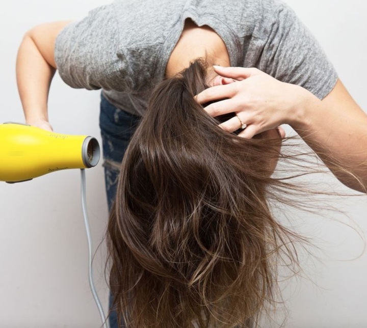 Blow drying your hair upside down is a simple way to help thin hair look fuller and more voluminous.
