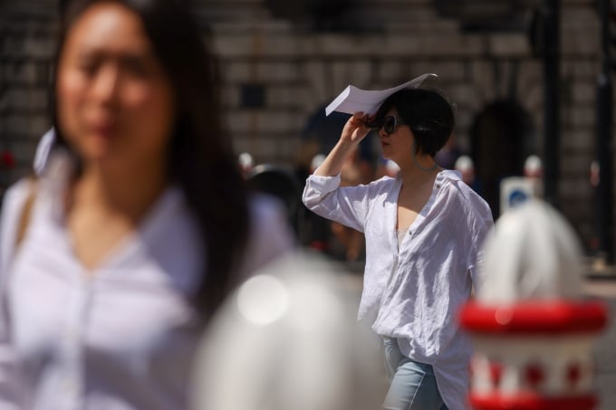 2022年7月、ロンドンで歩行者が日よけとして封筒を利用している。写真：ホリー・アダムス/ブルームバーグ
