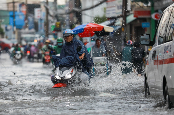 トゥドゥック市の浸水地域の一つ、トゥ・ゴック・ヴァン通りの浸水した道路でバイク乗りたちが苦戦している。写真: クイン・トラン