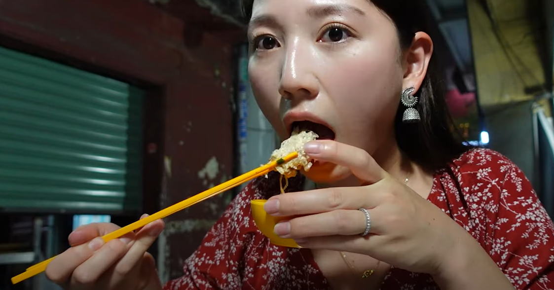 Japanese tourists taste a dish on a sidewalk in Ho Chi Minh City at night, praise it as 'the best I've ever eaten'