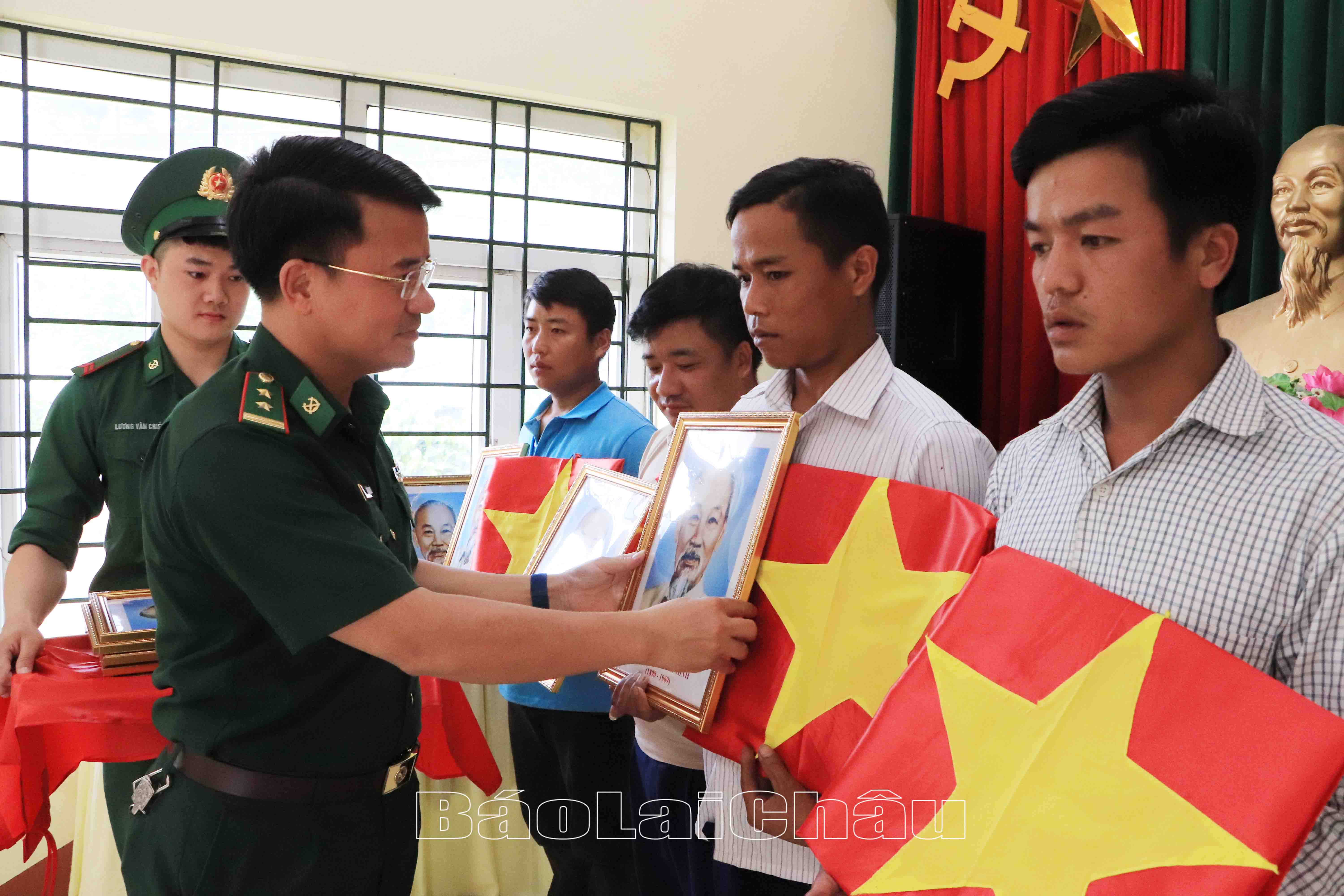 Đồng chí Trung tá Lê Văn Quyết – Đồn trưởng Đồn Biên phòng Huổi Luông trao ảnh Bác Hồ cho các trưởng bản.