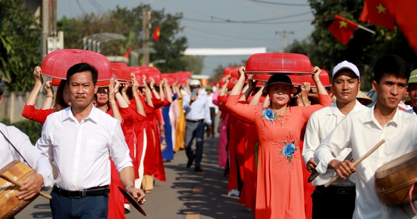 Las personas que visten Ao Dai y llevan bandejas de pasteles Chung en sus cabezas participan en un concurso en el aniversario de la muerte del rey Mai Hac De.