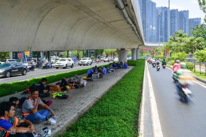 Durante la pausa del almuerzo, decenas de trabajadores comen y duermen bajo el puente Ba Son, en la calle Ton Duc Thang, distrito 1. Foto: Quynh Tran