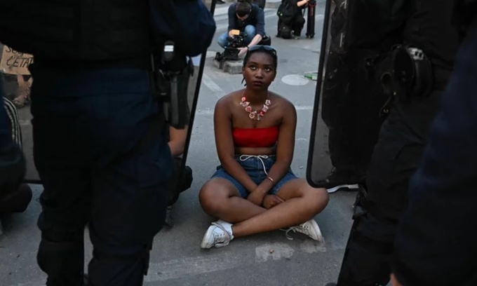 Người biểu tình ngồi trước cảnh sát chống bạo loạn ở Paris hôm 30/6. Ảnh: AFP