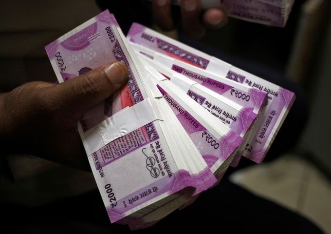 Ein Bankangestellter im indischen Jammu hält Bündel mit 2.000-Rupien-Scheinen in der Hand. Foto: Reuters