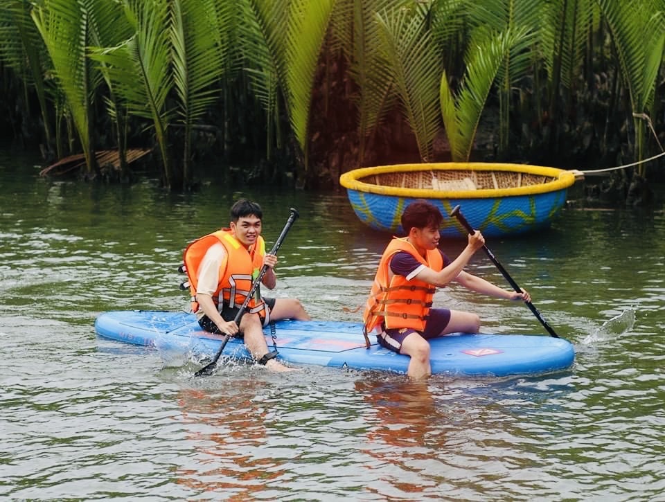 Tourists cross the river in the coconut forest.