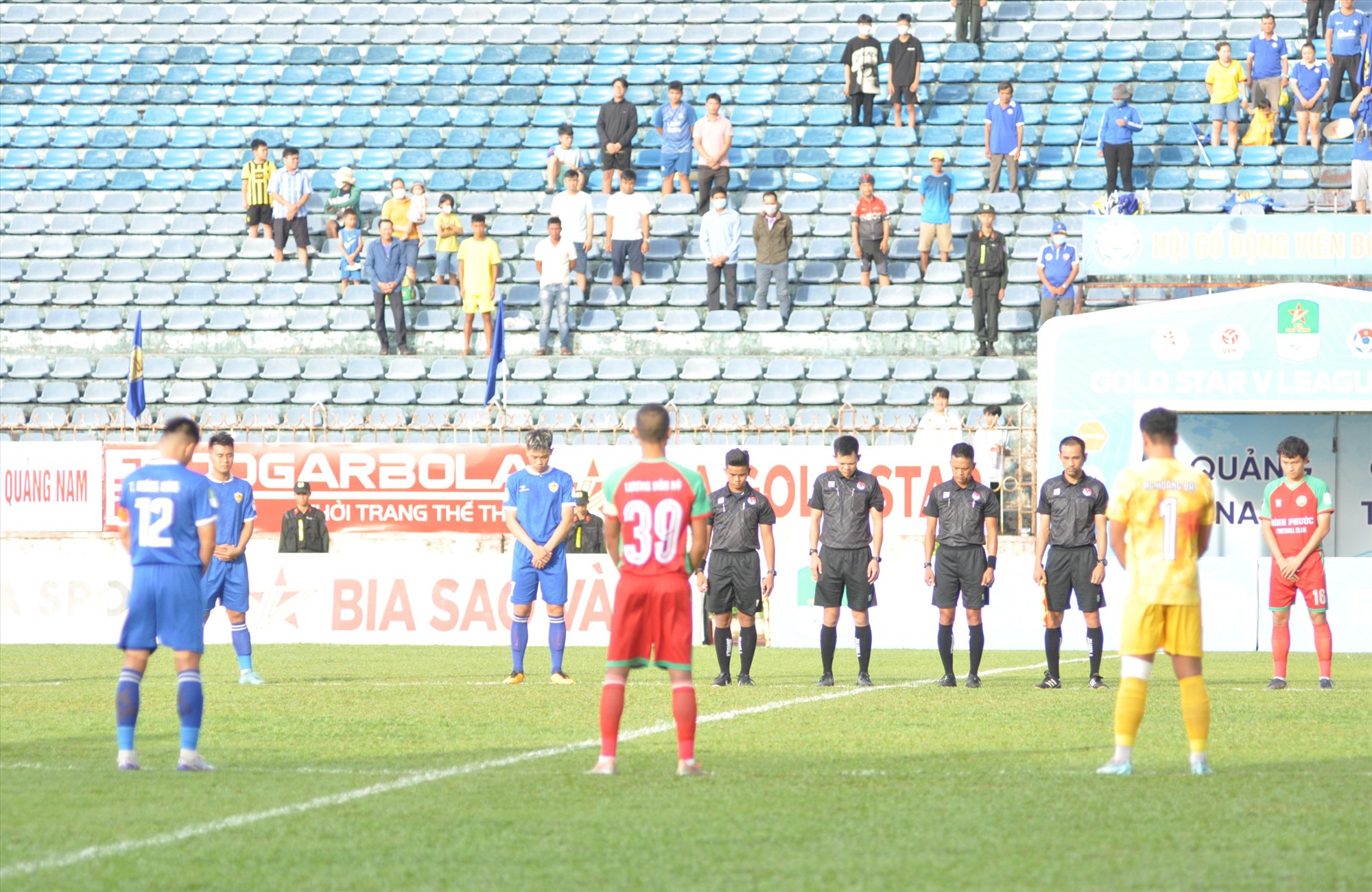 Los jugadores y espectadores del partido entre Quang Nam y Binh Phuoc observaron un minuto de silencio para conmemorar al jugador Vo Minh Hieu del equipo juvenil de Quang Nam, quien murió en un accidente de tráfico. Foto: T.V.