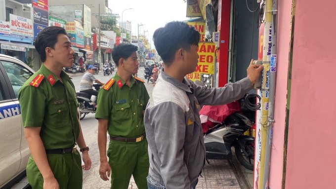 Công an quận 10 buộc người vi phạm gỡ quảng cáo rao vặt trên ống nước, hồi tháng 7. Ảnh: Minh Vân