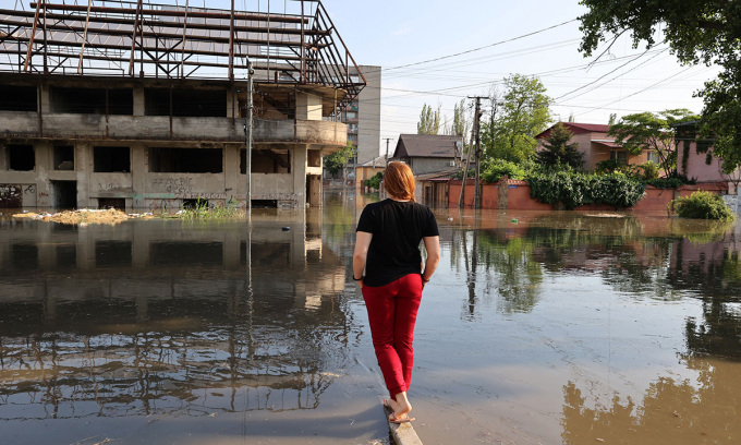 6月6日にカホフカダムが決壊した後、ヘルソンで冠水した道路を眺める女性。写真：AFP/ゲッティ