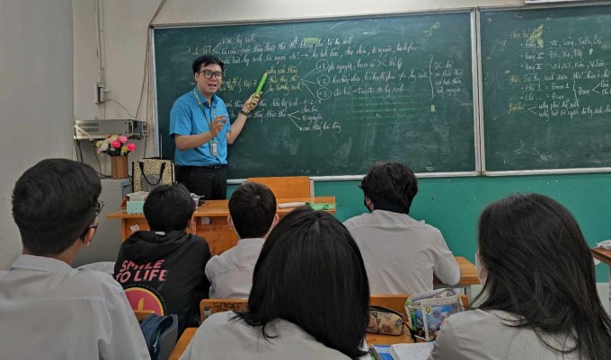 El profesor Vo Kim Bao revisa literatura para estudiantes en la escuela secundaria Nguyen Du, ciudad de Ho Chi Minh, el 16 de mayo. Foto: Personaje proporcionado