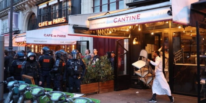 Một bồi bàn đang dọn dẹp lại cửa hàng sau cuộc bạo động ở Paris hôm 30/6. Ảnh: AFP