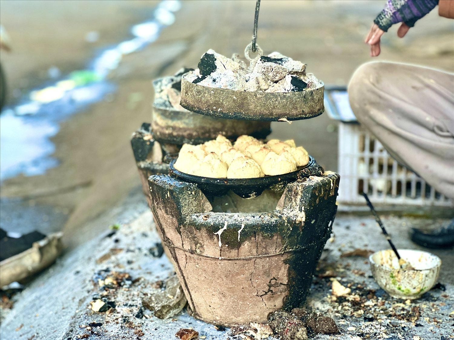 Người làm bánh dùng khuôn có lửa than phía trên để đậy lại nướng bánh thuẫn