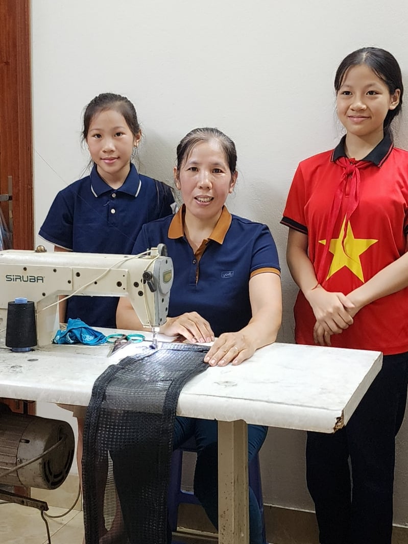 After school hours, two sisters Vuong Thi Ngoc Lan and Vuong Thi Thuy Linh help their mother sew nets to increase their income.