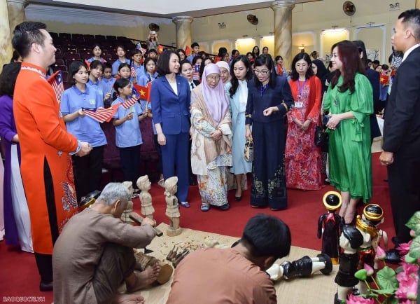 The two wives of the Prime Minister of Vietnam and the Prime Minister of Malaysia enjoy the art of water puppetry.