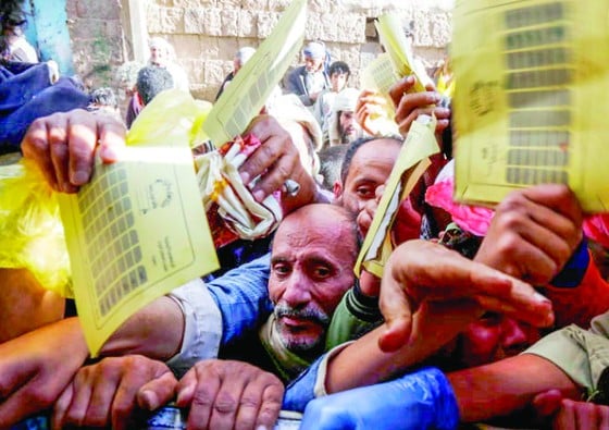 Yemeni people gather around a charity kitchen