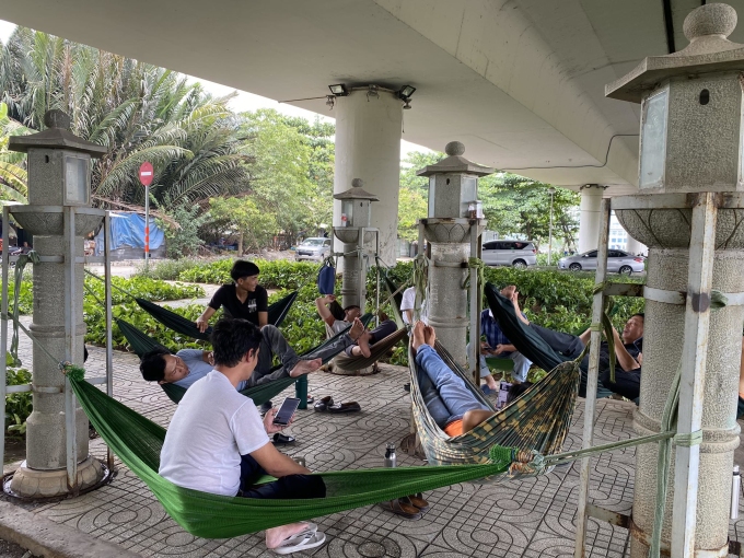 Un grupo de conductores toma un descanso para almorzar para evitar el calor bajo el puente Thu Thiem, ciudad de Thu Duc, mediodía del 10 de abril. Foto: Ngoc Ngan