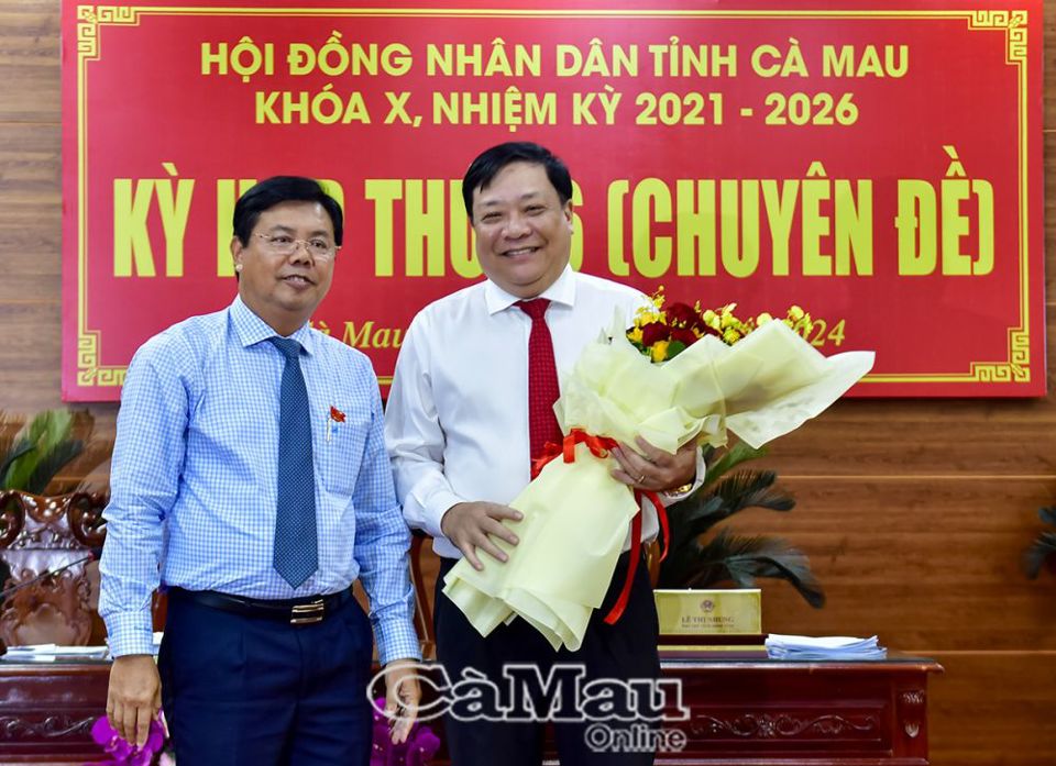 El camarada Nguyen Tien Hai, secretario del Comité Provincial del Partido y presidente del Consejo Popular de la provincia de Ca Mau, entregó flores para felicitar al nuevo presidente del Comité Popular Provincial, Pham Thanh Ngai. Foto: Ca Mau Online