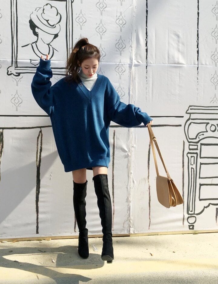 Mädchen sehen stylisch aus, wenn sie Pullover mit hohen Stiefeln kombinieren.