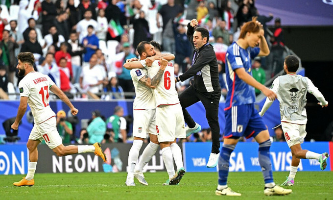 Defender Itakura holds his head, while Iranian players hug each other to celebrate the victory over Japan. Photo: AFP