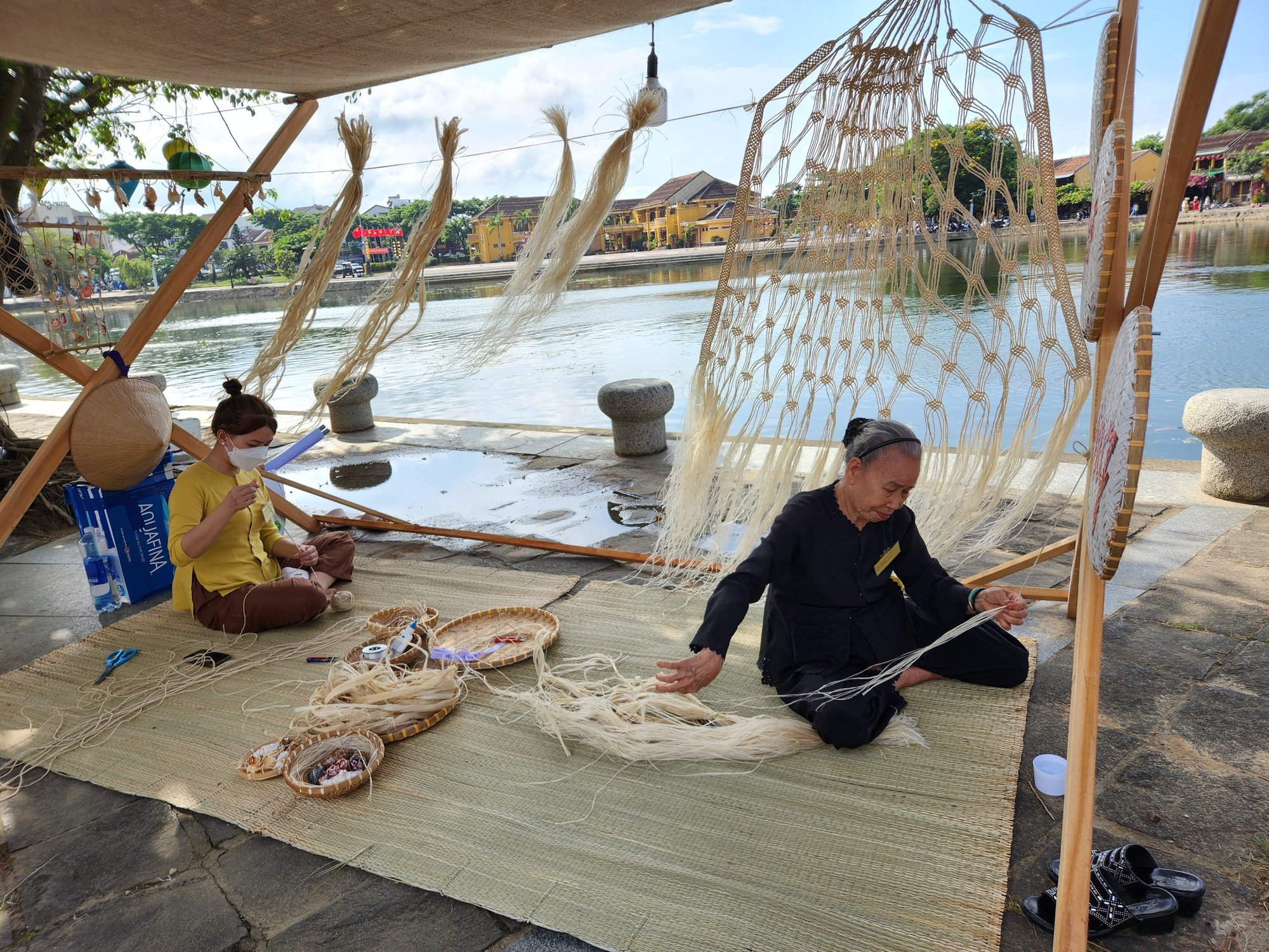 Nghệ nhân lớn tuổi ở Hội An trình diễn nghề đan võng từ cây ngô đồng tại phố đi bộ - Ảnh: Q.T.