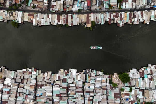 ホーチミン市の運河沿いに建てられた仮設住宅の対照的な風景写真1