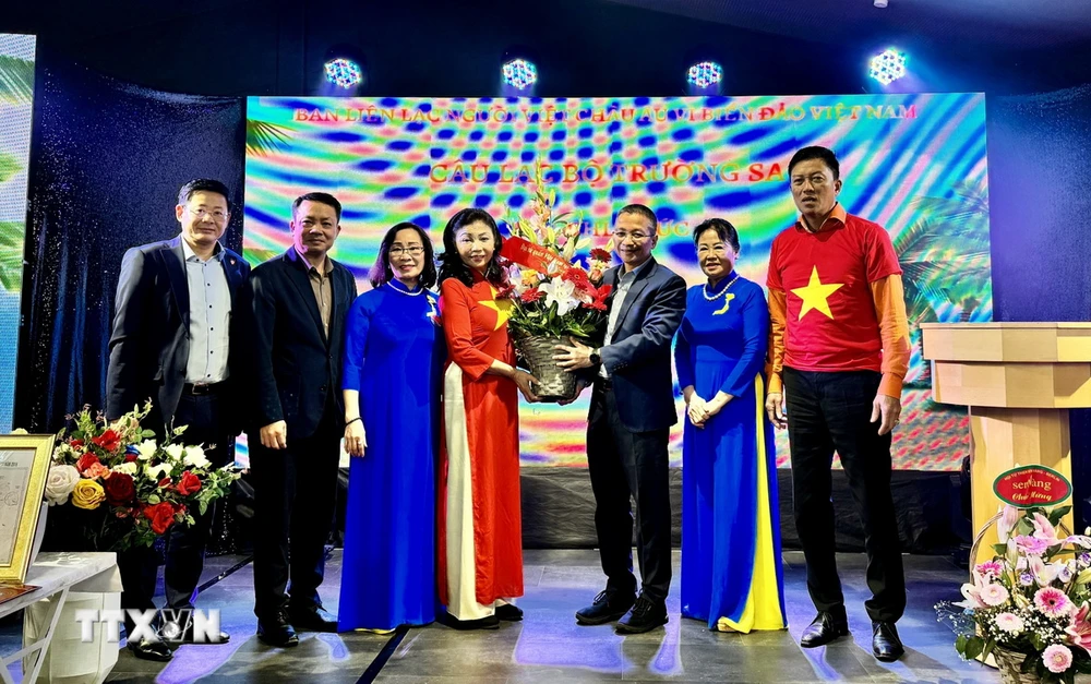 M. Chu Tuan Duc, conseiller de l'ambassade du Vietnam en Allemagne, a offert des fleurs à Mme Bui Thi Thu Minh, nouvelle chef du Comité de liaison euro-vietnamien « Pour les mers et les îles du Vietnam ». (Photo : Thu Hang/VNA)