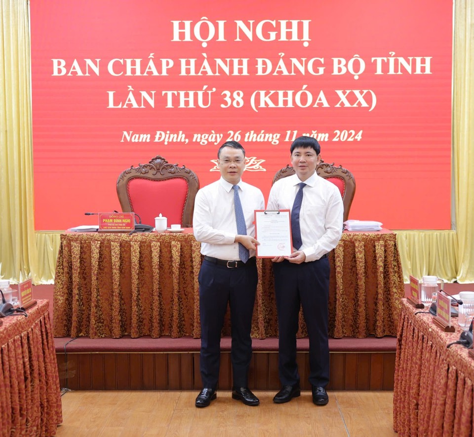 លេខាបក្សខេត្ត Nam Dinh លោក Dang Khanh Toan (ឆ្វេង) បង្ហាញសេចក្តីសម្រេចរបស់លេខាធិការដ្ឋានមជ្ឈឹមបក្សជូនលោក Nguyen Hoang Anh។ រូបថត៖ Duy Hung