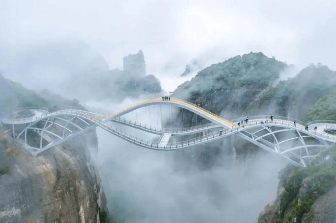 Wenn Besucher auf der Brücke stehen, können sie majestätische Berge, Wolken und grüne Bäume sehen. Es fühlt sich wirklich wie ein Märchenland an. Wenn Sie nach unten blicken, sehen Sie nur eine steile Klippe, die wie ein bodenloser Abgrund aussieht und bei allen, die den Nervenkitzel lieben, für Aufregung sorgt.