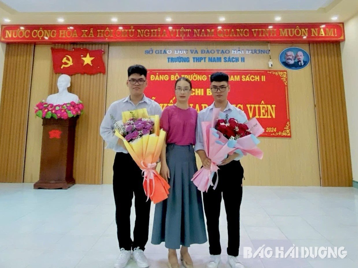 La professeure principale Nguyen Thi Binh prend une photo avec Tri et Dung.