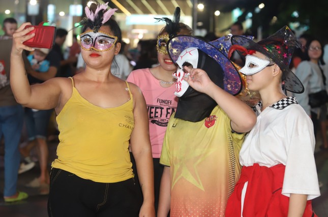 Junge Menschen werden in der Halloween-Nacht mit eindrucksvollen Kostümen umringt und fotografiert. Foto 2