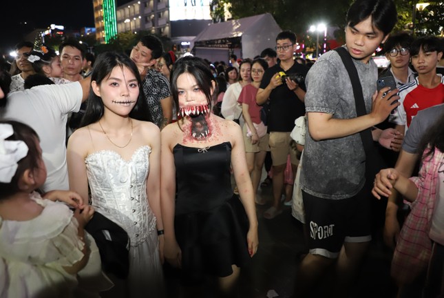 Junge Menschen sind umringt, um in der Halloween-Nacht in beeindruckenden Kostümen Fotos zu machen. Foto 3