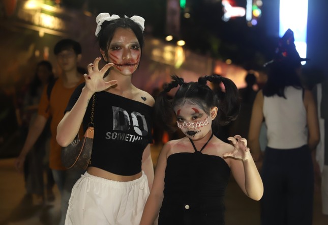 Junge Menschen sind umringt, um in der Halloween-Nacht in beeindruckenden Kostümen Fotos zu machen. Foto 6