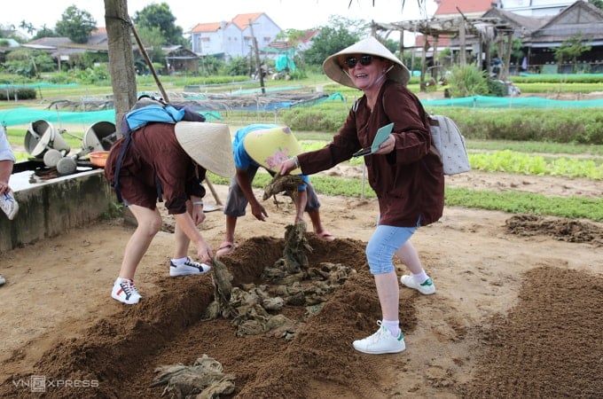 Du khách nước ngoài trải nghiệm trồng rau ở làng rau Trà Quế, Hội An. Ảnh: Đắc Thành