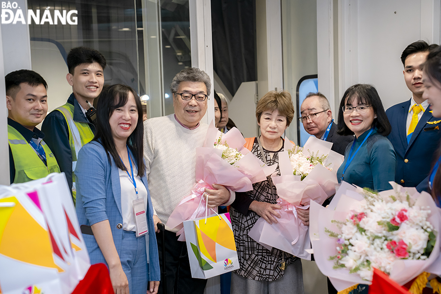 Đại diện Trung tâm Xúc tiến du lịch Đà Nẵng cùng đại diện lãnh đạo Vietravel chi nhánh Đà Nẵng đã đón tiếp tặng hoa, quà cho những du khách trên chuyến bay thuê chuyến. Ảnh: THU HÀ