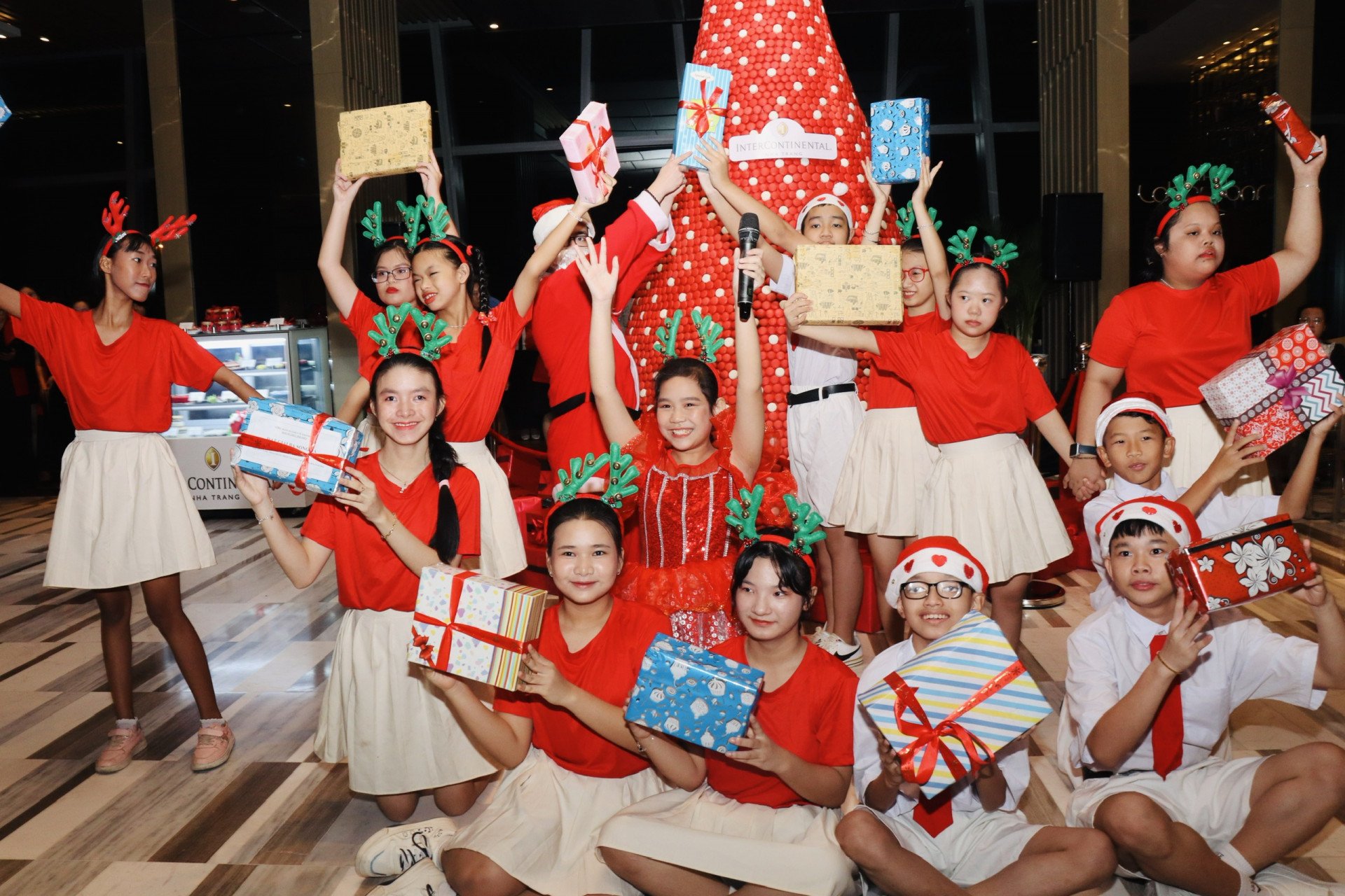 インターコンチネンタルホテルのマカロンクリスマスツリーの横で子供たちがクリスマスキャロルを歌っています