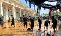 Soldados y milicianos se unen con maestros para limpiar el barro y la basura después de las inundaciones, para que los niños regresen a la escuela lo antes posible.