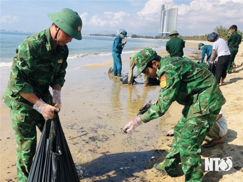 Thu gom vết dầu loang vón cục dạt vào bờ biển