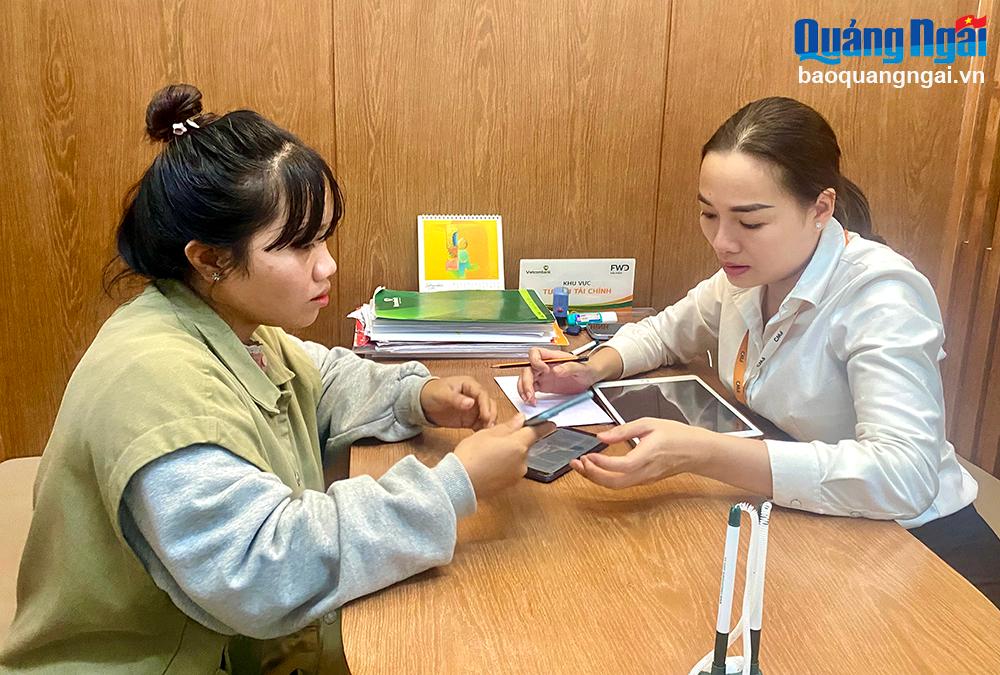 Nhân viên Phòng giao dịch Vietcombank Hùng Vương (TP.Quảng Ngãi) hướng dẫn khách hàng cài đặt, sử dụng các dịch vụ ngân hàng điện tử. Ảnh: T.L
