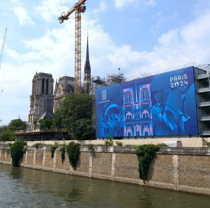 Ein Teil der Wand der Kathedrale Notre-Dame in Paris war am 21. Juni mit einem neuen Plakat bedeckt, das die Olympischen und Paralympischen Spiele sowie die Wiedereröffnung der Kathedrale im Dezember feierte. Foto: Notre-Dame de Paris.