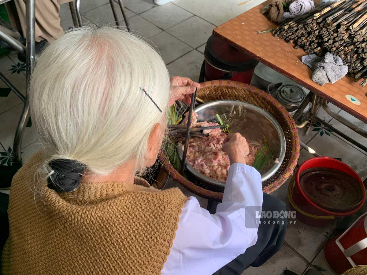 친 씨(94세)는 자녀와 손주들이 대나무 꼬치에 고기를 꽂아 구워 먹는 것을 돕고 있다. 사진: 하비