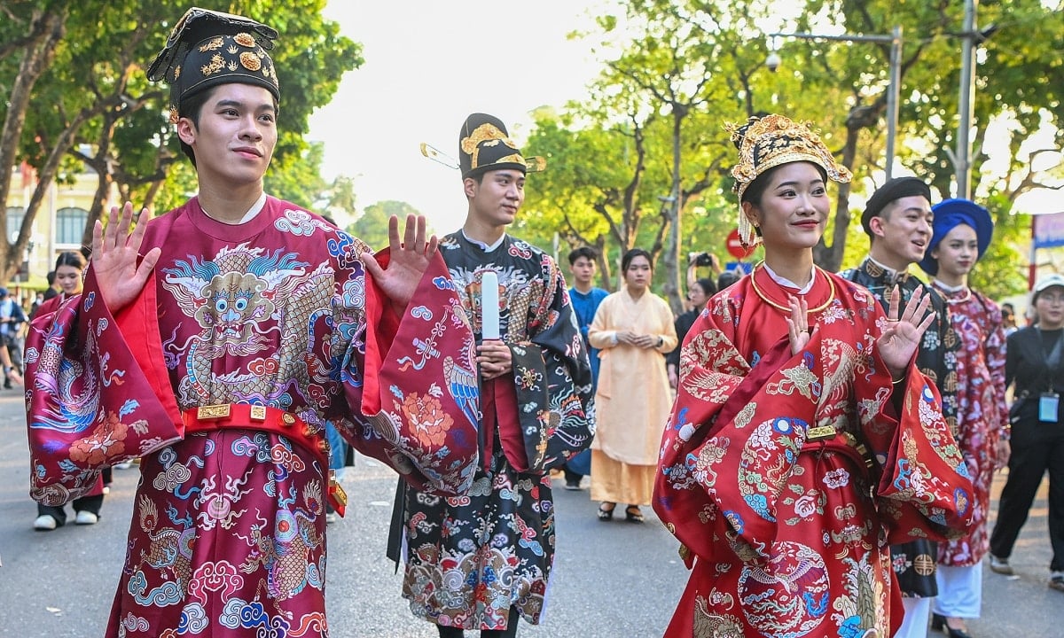 수백 명의 사람들이 하노이의 보행자 거리에서 전통 의상을 입고 퍼레이드를 벌인다.