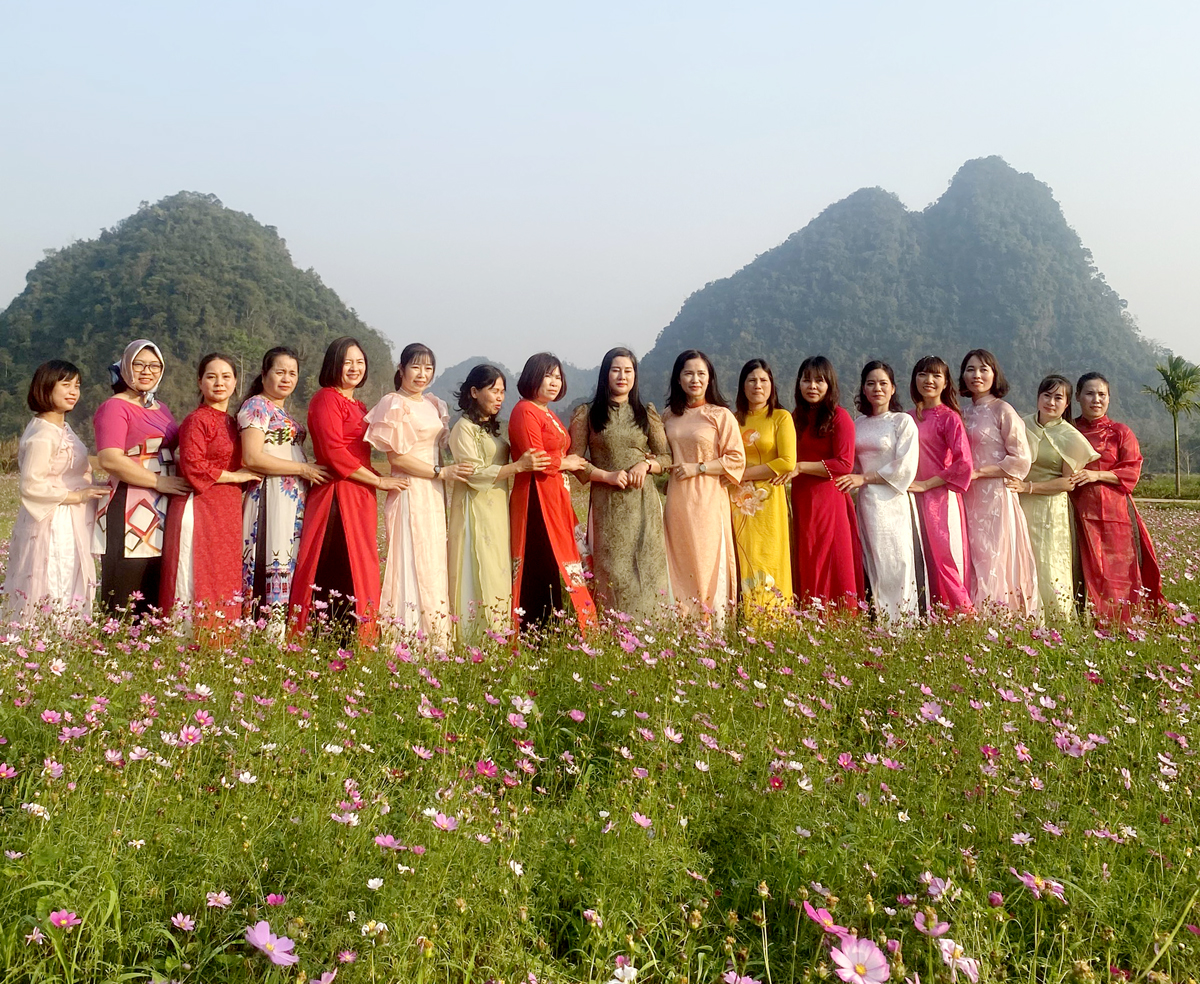 Du khách diện trang phục truyền thống người Mông tạo dáng bên hoa.