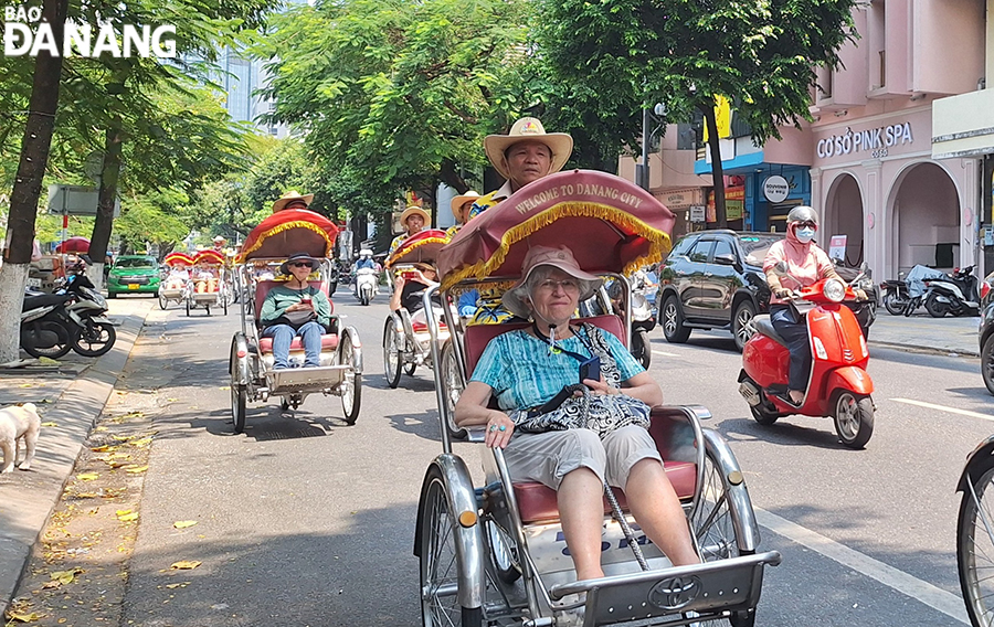 Nhiều du khách tàu biển thích thú lựa chọn trải nghiệm tham quan Đà Nẵng bằng xích lô. Trong ảnh: Du khách tham quan quanh Đà Nẵng bằng xích lô. Ảnh: THU HÀ.