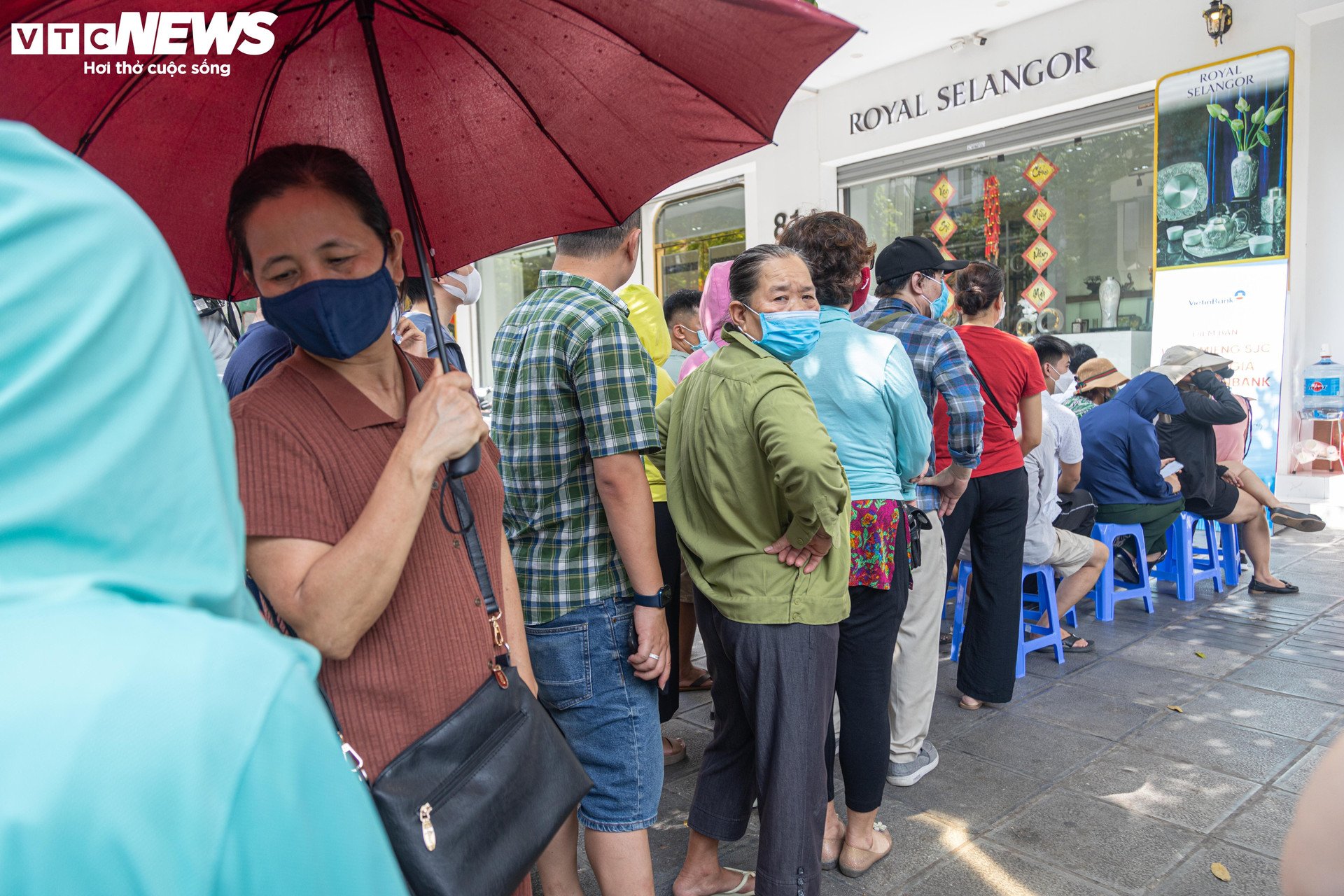 Los clientes esperan bajo el sol para comprar oro en el punto de venta de Vietinbank.