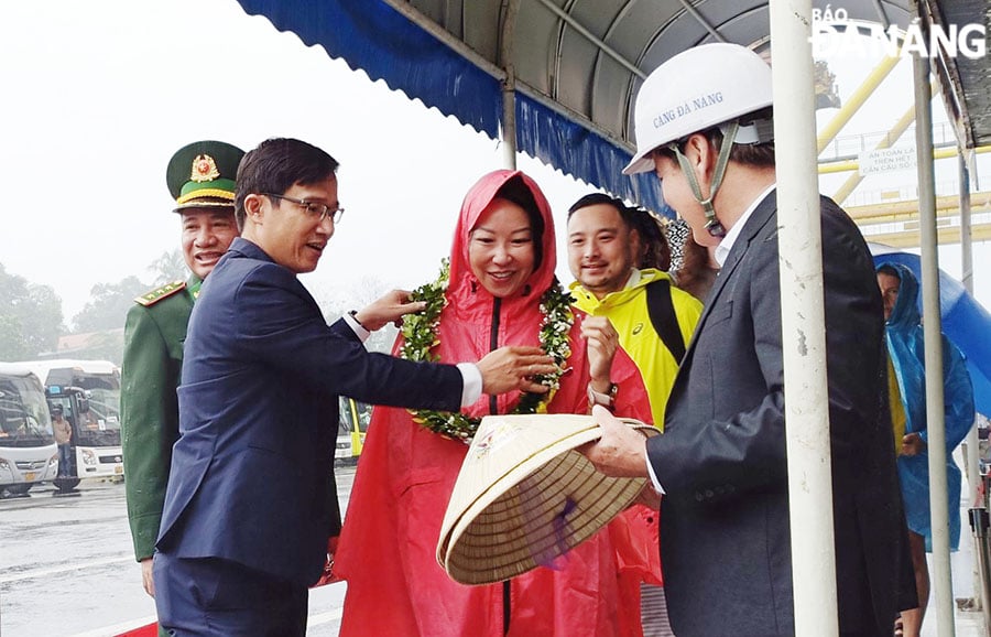 Đại diện lãnh đạo thành phố  tặng hoa, quà cho những vị khách tàu biển đầu tiên ngày năm mới. Ảnh: THU HÀ