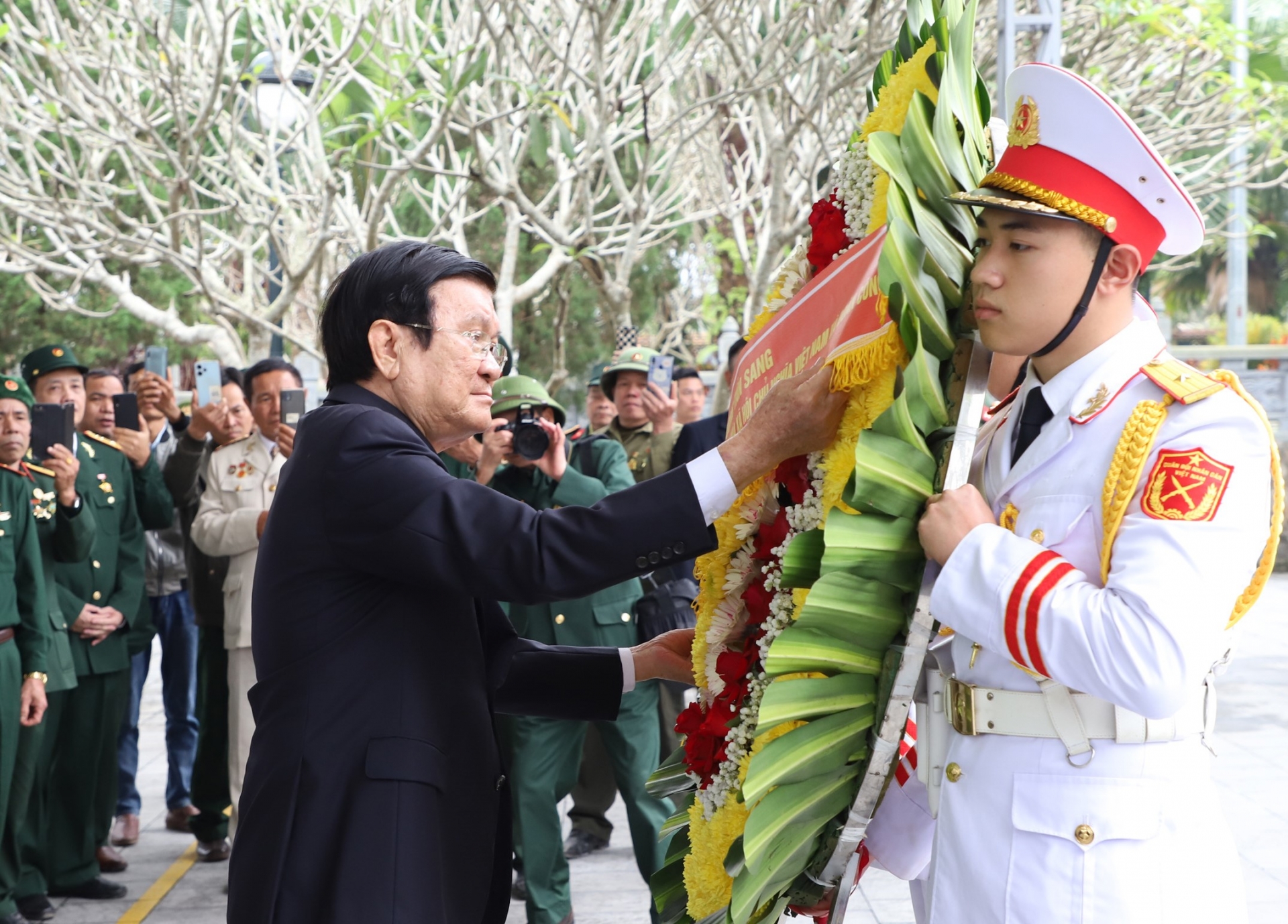 Der ehemalige Präsident Truong Tan Sang richtet den Kranz, bevor er ihn am Ehrendenkmal des Vaterlandes auf dem Vi Xuyen National Martyrs Cemetery niederlegt.