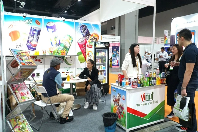 Besucher besuchen den Stand mit Fruchtsaftkonserven der Vinut Company auf der Malaysia Food and Beverage Exhibition. (Foto: Hang Linh/VNA)