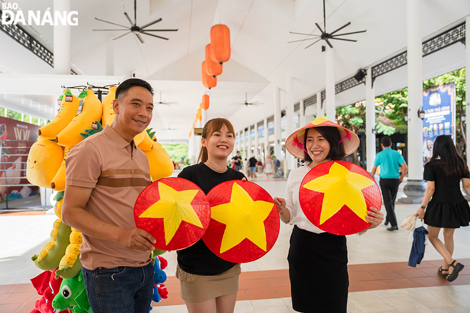 นักท่องเที่ยวจำนวนมากเพลิดเพลินกับการเช็คอินด้วยการสวมเสื้อธงสีแดงและดาวสีเหลือง และหมวกทรงกรวยประดับธงสีแดงและดาวสีเหลือง ภาพ: พฤ.